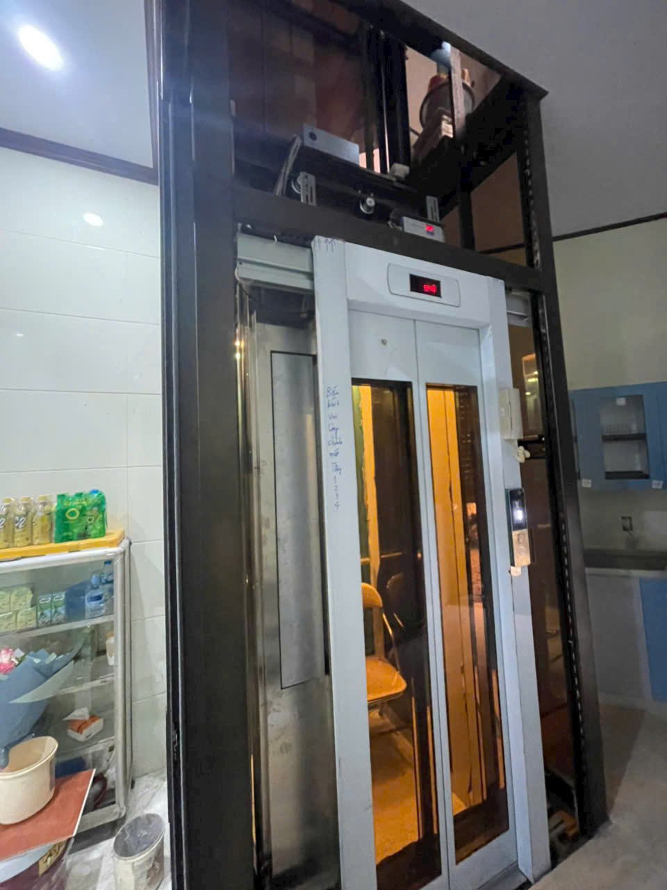 Thang máy gia đình khung thép cửa kính màu vàng lắp đặt trong không gian bếp nhà ở